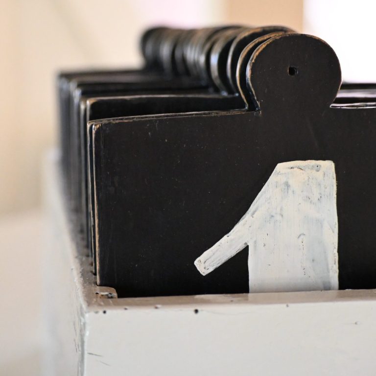 Schwarze Holztäfelchen in Reihe, mittig mit einer weißen Nummer eins.