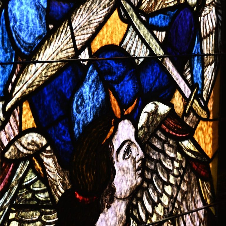 Detail eines bunten Kirchenfensters mit Engeln und blauem Hintergrund.