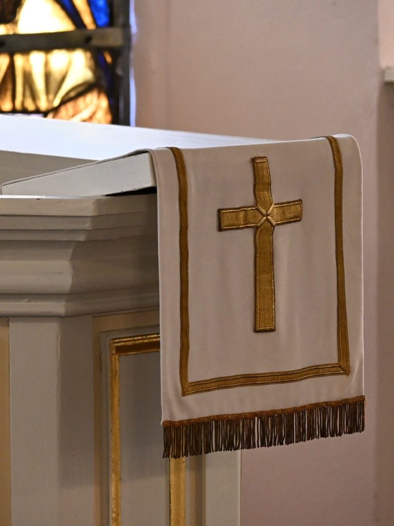 Altar mit einer goldenen gekreuzten Verzierung auf einem weißen Tuch.