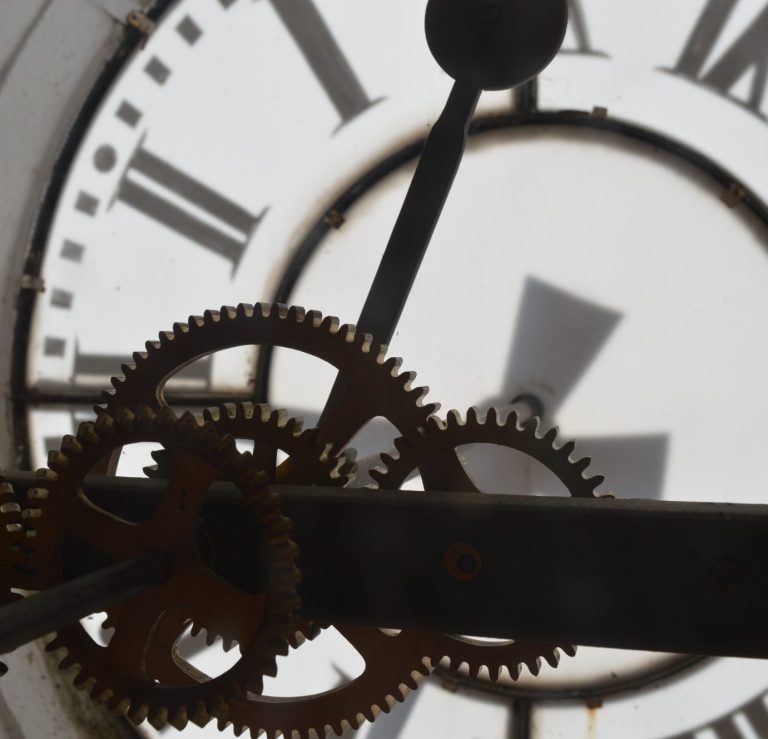 Kirche mit spitzem Turm, umgeben von bunten Blumen und blauen Himmel.